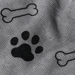 Detalle del estampado de huesos y huellas sobre la microfibra gris de la toalla Calmora